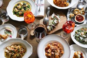 a wooden table with plates of food and glasses of wine at Kimpton Hotel Vintage Portland by IHG in Portland