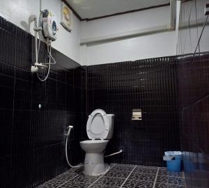 a bathroom with a toilet in a black tiled wall at ณ สุข รีสอร์ท (Nasuk resort) in Khon Kaen