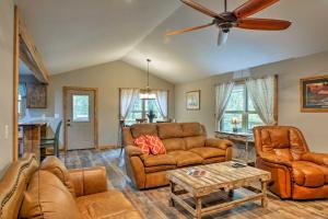 a living room with leather furniture and a ceiling fan at Summerville Getaway with Deck and On-Site Creek! in Summerville