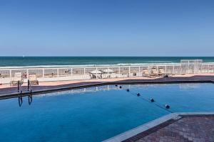 a large swimming pool with the beach in the background at Waterfront Daytona Beach Shores Condo with Amenities in Daytona Beach Shores