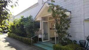 une maison avec une porte d'entrée et une terrasse couverte dans l'établissement ペンション ラリー, à Kawazu