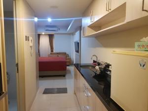 a kitchen with a sink and a room with a bed at #7 Apartemen The Pinnacle - Louis Kienne Pandanaran Semarang in Semarang
