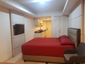 a bedroom with a red bed and a television at #7 Apartemen The Pinnacle - Louis Kienne Pandanaran Semarang in Semarang