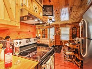 a kitchen with a stove and a dining room with a table at Log Cabin Studio in Sevierville with Deck and Hot Tub! in Sevierville