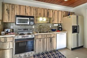a kitchen with wooden cabinets and a white refrigerator at Indian Shores Cottage with Cabana - Steps to Beach! in Clearwater Beach