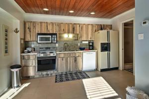 a kitchen with wooden cabinets and a white refrigerator at Indian Shores Cottage with Cabana - Steps to Beach! in Clearwater Beach