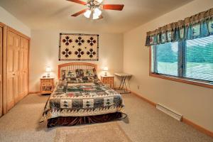 a bedroom with a bed and a ceiling fan at Rapid River Log Cabin with Loft on 160 Scenic Acres! in Gladstone