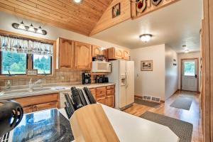 a kitchen with wooden cabinets and a white refrigerator at Rapid River Log Cabin with Loft on 160 Scenic Acres! in Gladstone