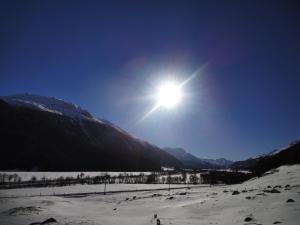 eine Sonne, die am Himmel über einen schneebedeckten Berg scheint in der Unterkunft Residenz La Mora in La Punt-Chamues-ch