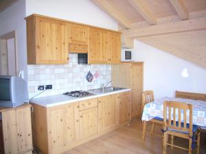 a kitchen with wooden cabinets and a sink and a table at Casa Davarda in Vigo di Fassa +15 photos