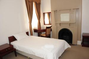 1 dormitorio con cama blanca y chimenea en Railway Bistro - Kandos, en Kandos