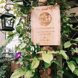 un panneau sur le côté d'un bâtiment avec des plantes dans l'établissement Kyono Mori Yurinsha, à Kyoto