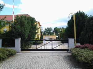 ein schwarzes Tor auf einem steinernen Gehweg vor einem Gebäude in der Unterkunft Leier Business Hotel in Gönyů