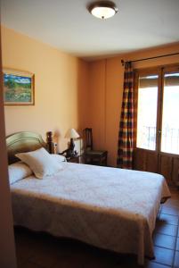 a bedroom with a bed and a desk and a window at Casa Rural El Arranca in Riópar