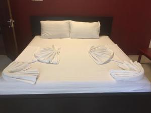 Una cama con sábanas blancas y sombrillas. en Nallur Residence, en Jaffna