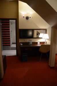um quarto de hotel com uma secretária, uma televisão e uma cadeira em Agat Hotel em Łódź