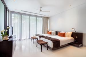a bedroom with a large bed and a large window at Twinpalms Phuket in Surin Beach