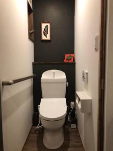 a bathroom with a white toilet and a black wall at むつわ柒 in Kanazawa