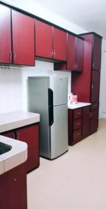 uma cozinha com armários vermelhos e um frigorífico de aço inoxidável em Homestay Mama Razzin em Kuala Kangsar