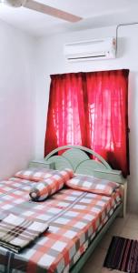 uma cama num quarto com uma cortina vermelha em Homestay Mama Razzin em Kuala Kangsar
