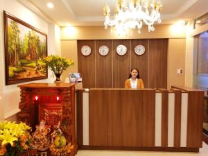 una mujer de pie detrás de una recepción en una habitación en Thien Ly Hotel - Da Lat Center en Dalat