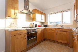 a kitchen with wooden cabinets and a stove top oven at Amersham Park Apartment in Manchester