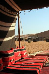 un groupe de sacs rouges et blancs assis sur une plage dans l'établissement Nomadic Desert Camp, à Al Wāşil