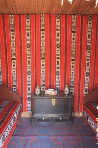 Cette chambre est dotée d'un mur rouge et blanc avec une table. dans l'établissement Nomadic Desert Camp, à Al Wāşil