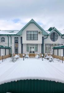 ein Haus mit einem grünen Zaun im Schnee in der Unterkunft B&B Lake House Hotel in Yusufkhona