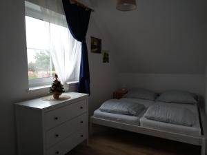 sypialnia z łóżkiem z komodą i oknem w obiekcie Domek w Białej - Bławatek w mieście Marcinowice