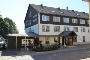 a large black and white building with tables and chairs at Hotel Lowen by Mastiff in Sankt Märgen