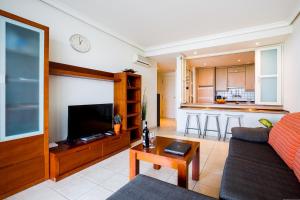 a living room with a couch and a tv and a kitchen at Apartamentos Balcon de Los Gigantes in Puerto de Santiago