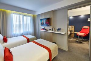 um quarto de hotel com duas camas e uma cadeira vermelha em Holiday Inn Express - Istanbul - Atakoy Metro, an IHG Hotel em Istambul