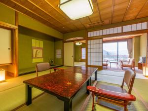 Yamashiro Onsen Miyabi no Yado Kaga Hyakumangoku في كجا: غرفة طعام مع طاولة وكراسي خشبية