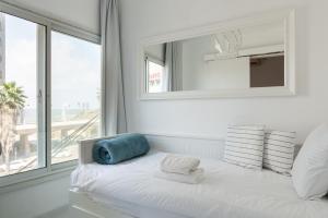 uma cama branca com um espelho e uma janela em Sea View 2 bedroom apartment with Bomb Shelter em Tel Aviv