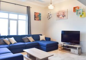 a living room with a blue couch and a tv at Muscat Villa in Muscat