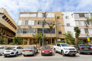 um grupo de carros estacionados num parque de estacionamento em frente a um edifício em Sea View 2 bedroom apartment with Bomb Shelter em Tel Aviv