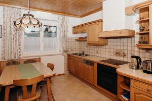 une cuisine avec des armoires en bois et une table avec des chaises dans l'établissement Ferienwohnung Hartlieb Goldeck Millstättersee, à Spittal an der Drau