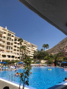 a large swimming pool with people in a resort at Castle Margherita's Apartments in Los Cristianos