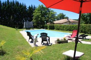 einen Pool mit Stühlen und einem Sonnenschirm in einem Hof in der Unterkunft la perle du lot gite 5 places in Castelnau-de-Montratier