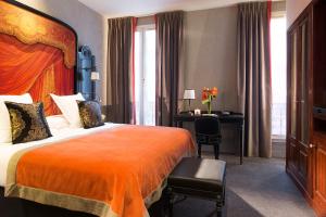 ein Hotelzimmer mit einem Bett und einem Schreibtisch in der Unterkunft Le Belmont Paris in Paris