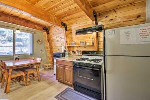 a kitchen and dining room with a stove and a table at Cabin with Deck and Hot Tub Walk to Big Bear Lake! in Fawnskin