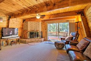 a living room with a couch and a tv and a fireplace at Cabin with Deck and Hot Tub Walk to Big Bear Lake! in Fawnskin