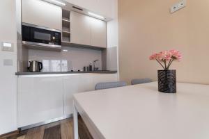a white kitchen with a vase of flowers on a table at Bilkova Old Town Residence in Prague