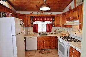 cocina con armarios de madera y nevera blanca en South Londonderry Home, Walk to Magic Mtn Ski Area, en Londonderry