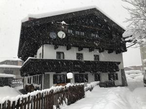 a house covered in snow in front of a fence at Aparts33 in Längenfeld
