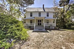 ein altes weißes Haus mit einer Veranda und Bäumen in der Unterkunft Peaceful Pomona Park Home 1 Mi to Lake Broward! in Satsuma