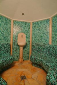 a bathroom with a toilet and green tiled walls at Hotel Brückenwirt - Al Ponte in Montagna