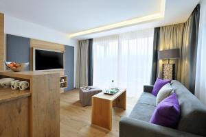 a living room with a couch and a tv at Sunnsait - Appartements für Genießer in Maria Alm am Steinernen Meer