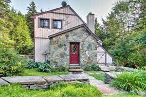 a stone cottage with a red door in a garden at West Dover Vacation Rental with Hot Tub Near Mt Snow in West Dover